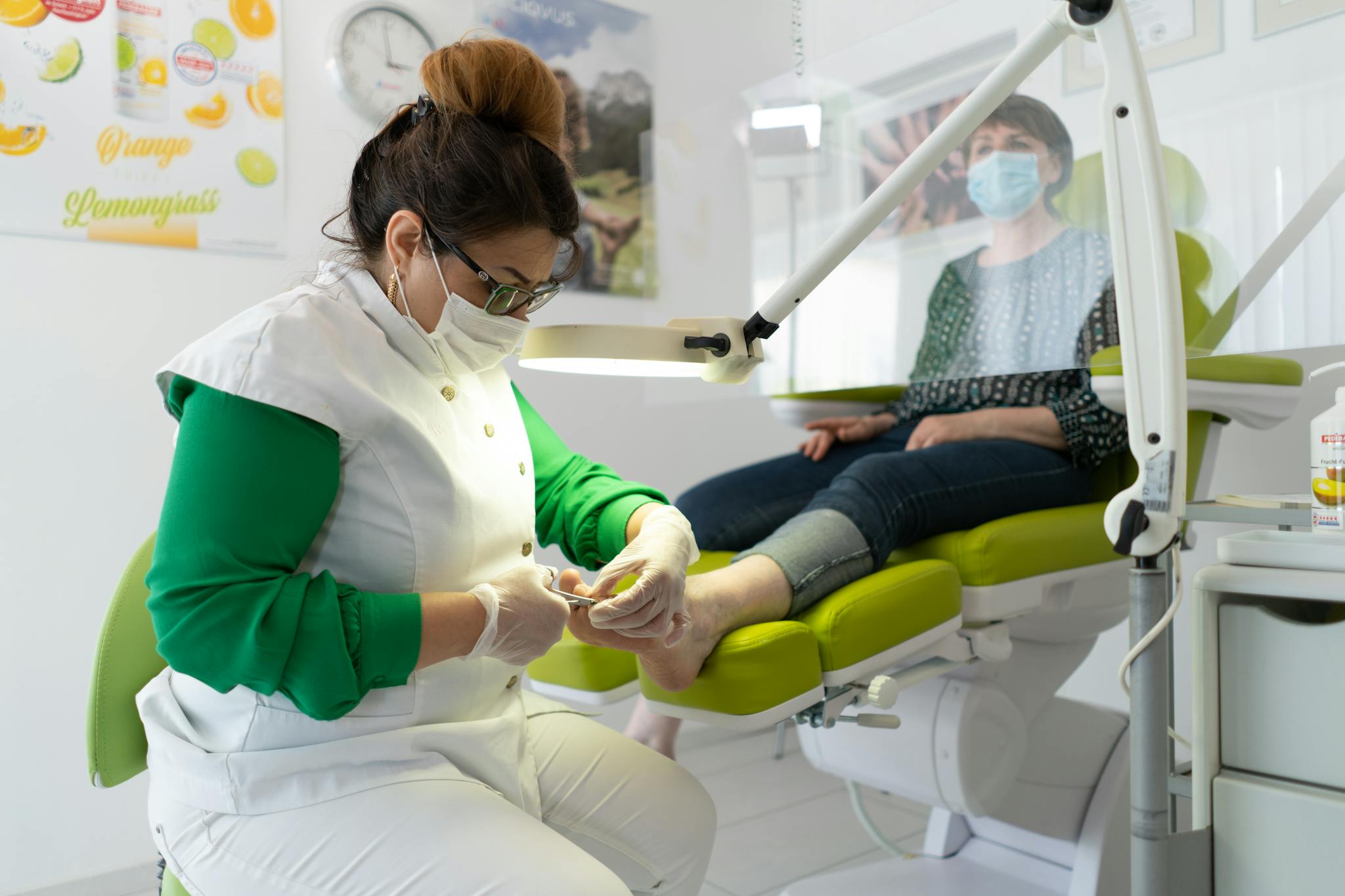 Concentrated professional master in beauty salon wearing medical mask doing pedicure  during coronavirus epidemic